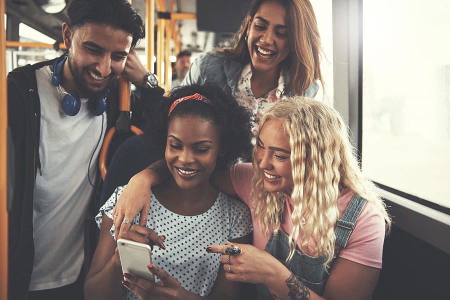 group of people gathered around a phone, laughing at social media content