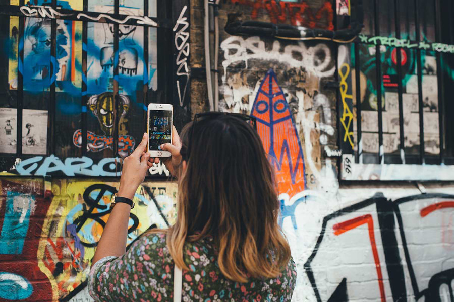 woman taking a photo of street art on her photo for Social Media