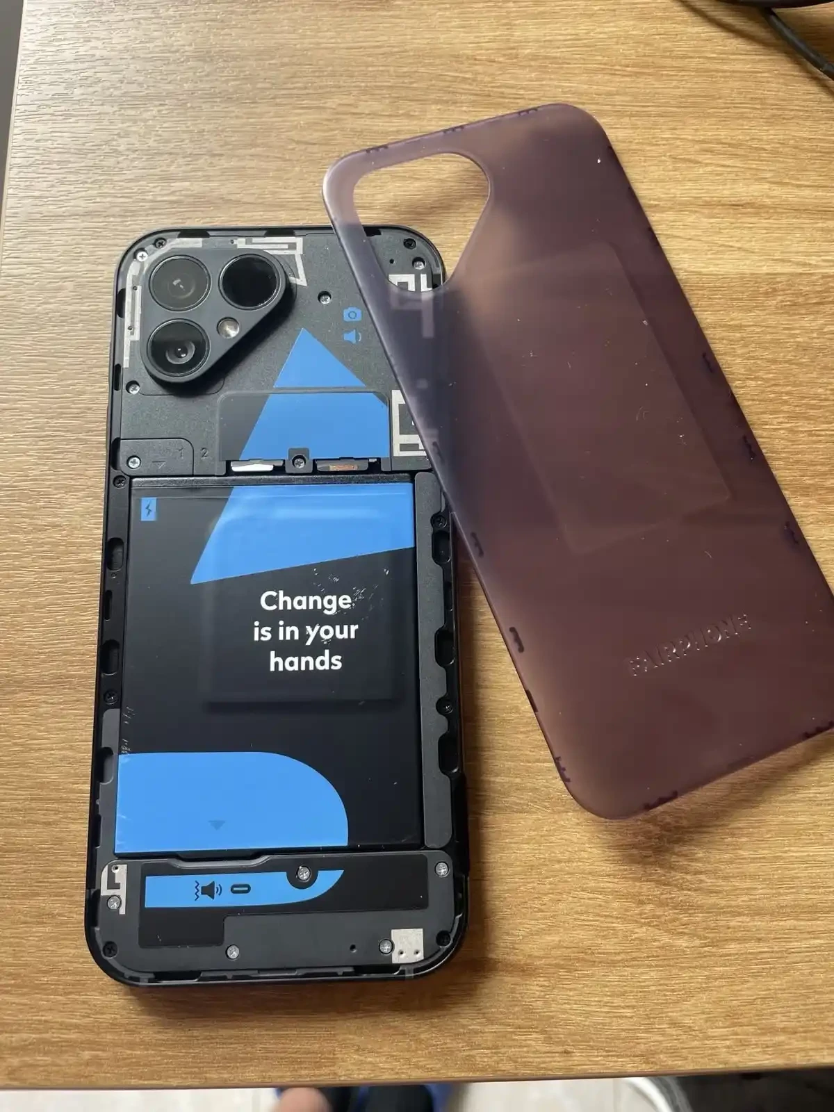 An image of the back of my Fairphone 5. I've taken off the transparent back using my fingernail (easy to do). The battery is visible, in addition to parts of the SIM card and the MicroSD card.